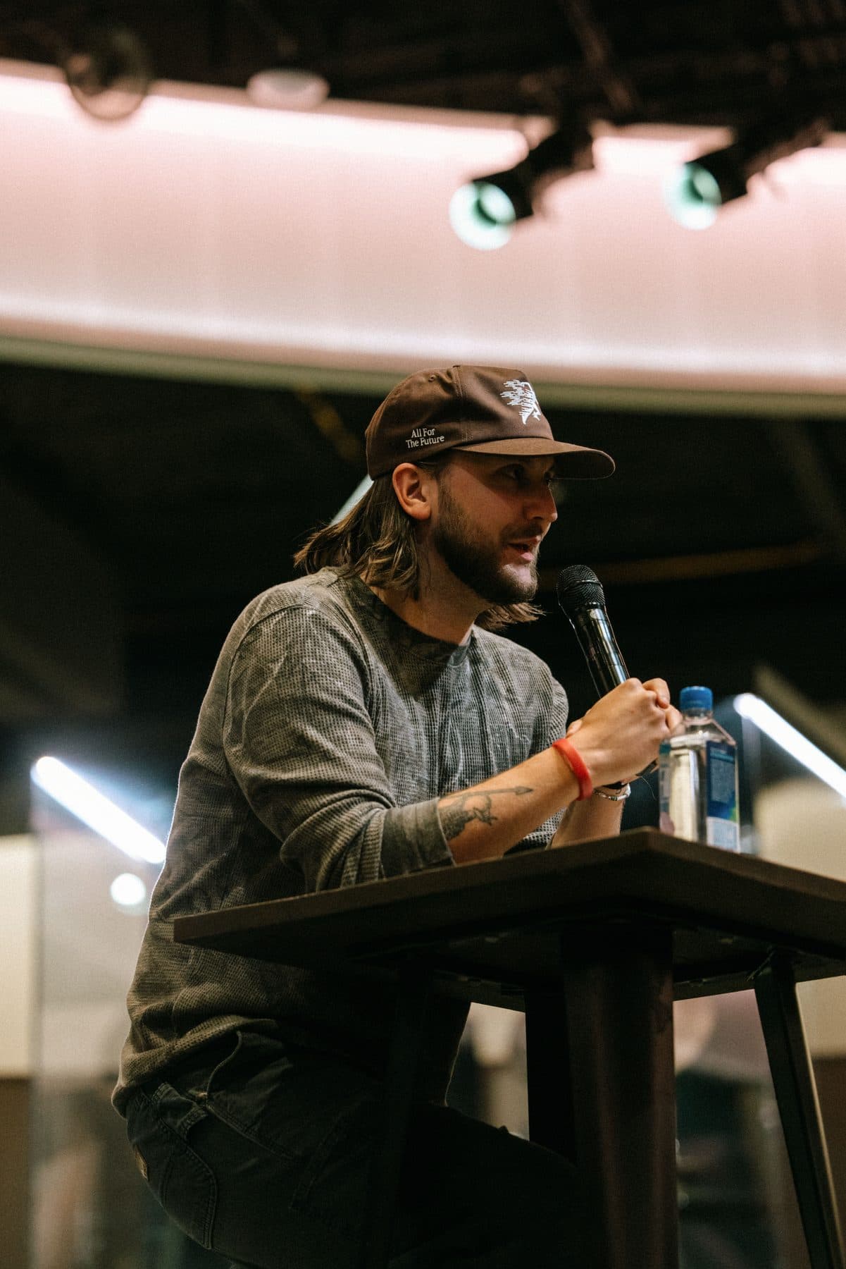 Chase seated at a high table, speaking into a microphone at UPPERROOM